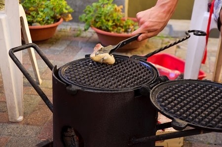 l’addetto unge le due piastre del Goufriér con un grosso pezzo di lardo ammollato nell’olio