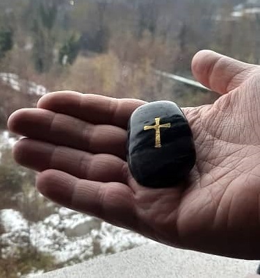 Pietra nera con croce incisa nella mano